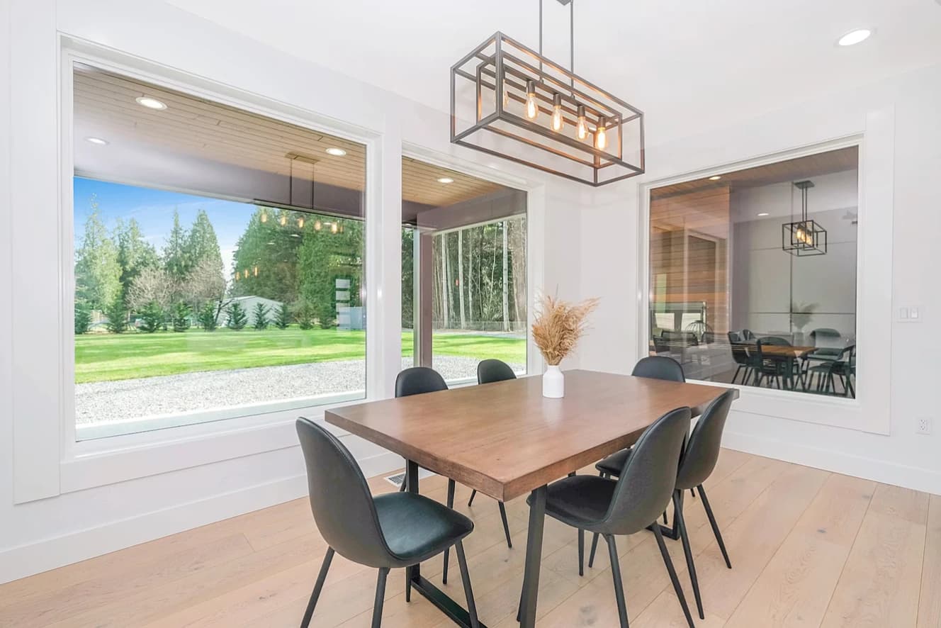 Dining room with a large window overlooking the lawn and the forest beyond